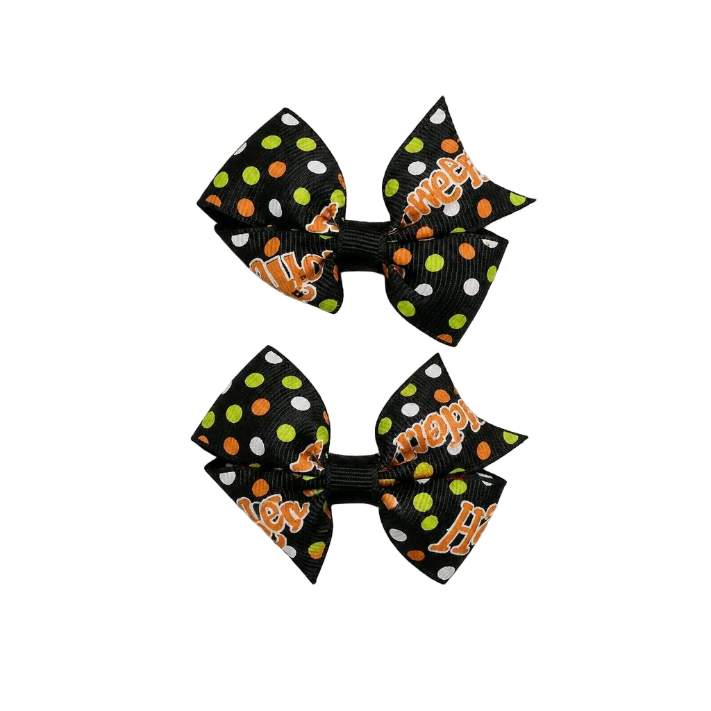 Two black hair bows with orange and green polka dots on a light gray background