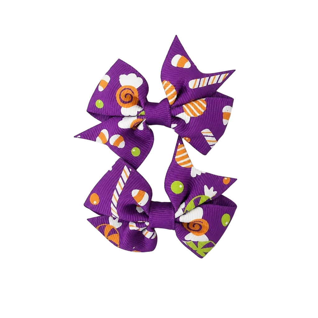 Purple hair bows with Halloween-themed designs on a light gray background