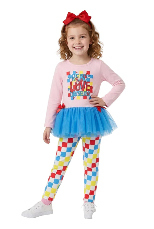 Young girl wearing a pink long-sleeve shirt with colorful text, blue tutu, and checkered leggings on a white background.