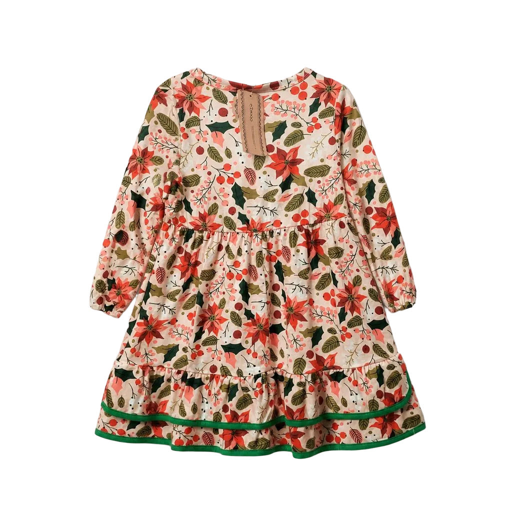 A long-sleeve tiered dress with a festive floral print featuring red poinsettias, green leaves, and berries on a cream background, finished with a green ruffled hem.