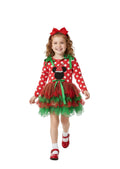 Child wearing a festive red and green dress with a bow, standing against a white background.