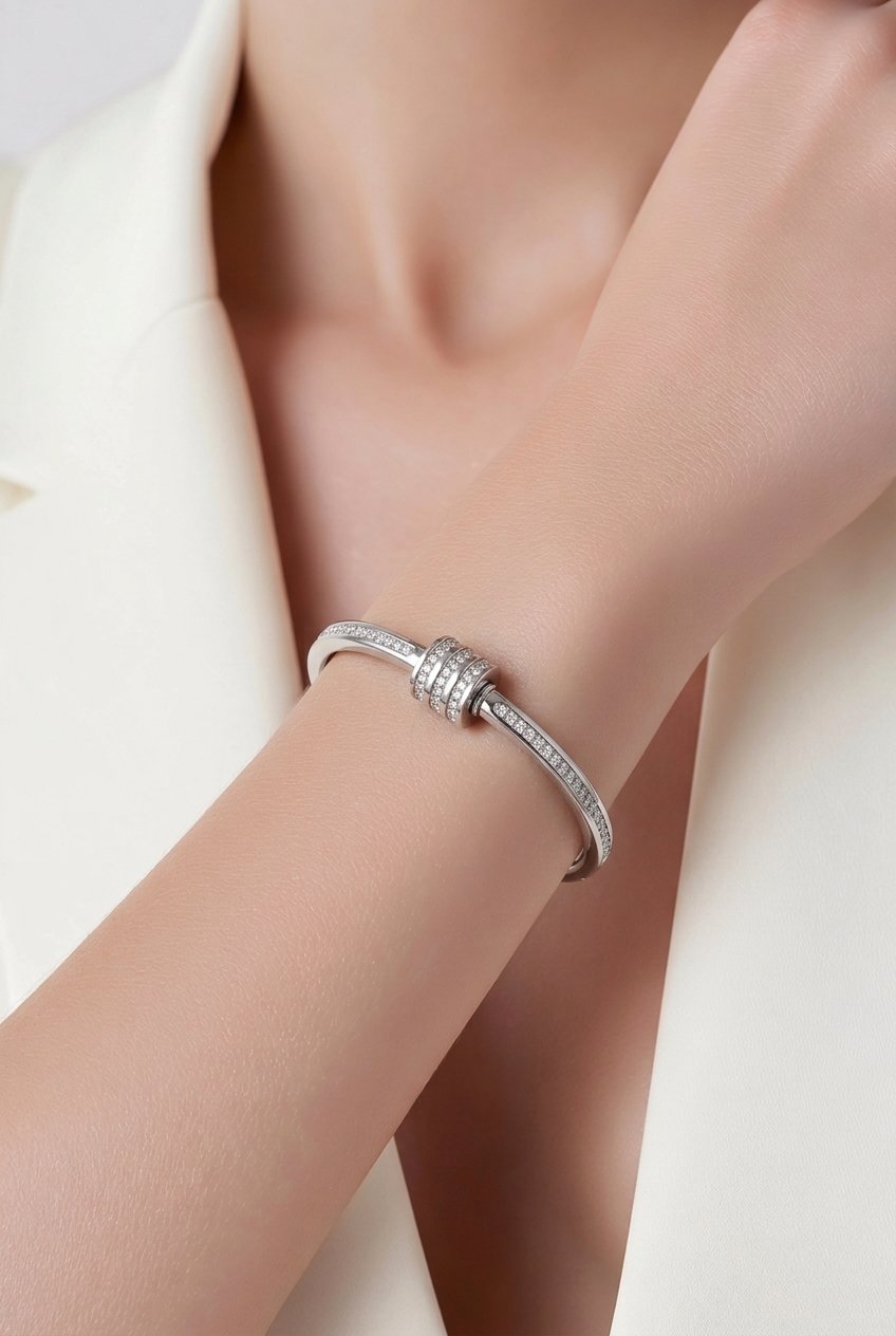 Silver bracelet with a diamond on a person's wrist against a neutral background