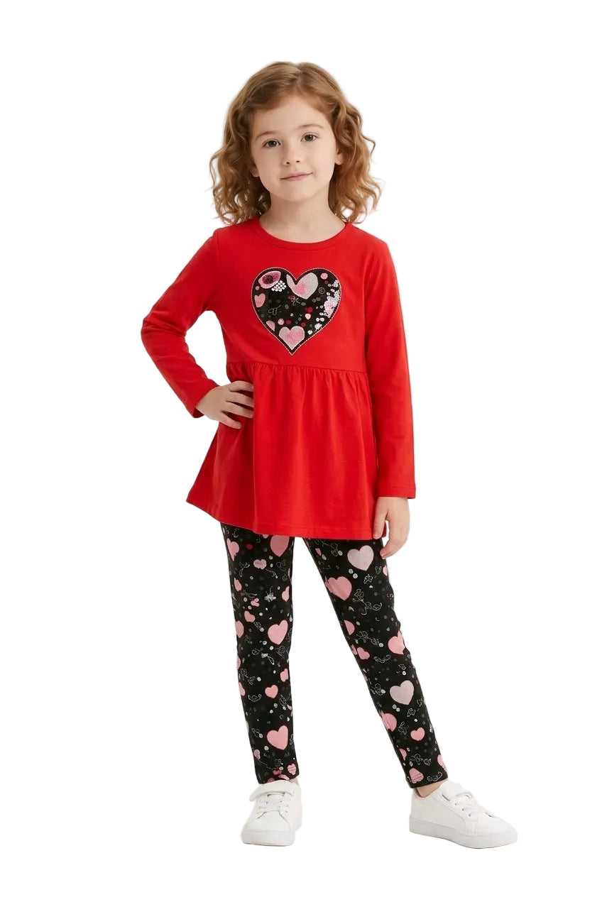 Young girl wearing a red top with a heart design and black leggings with pink hearts on a white background