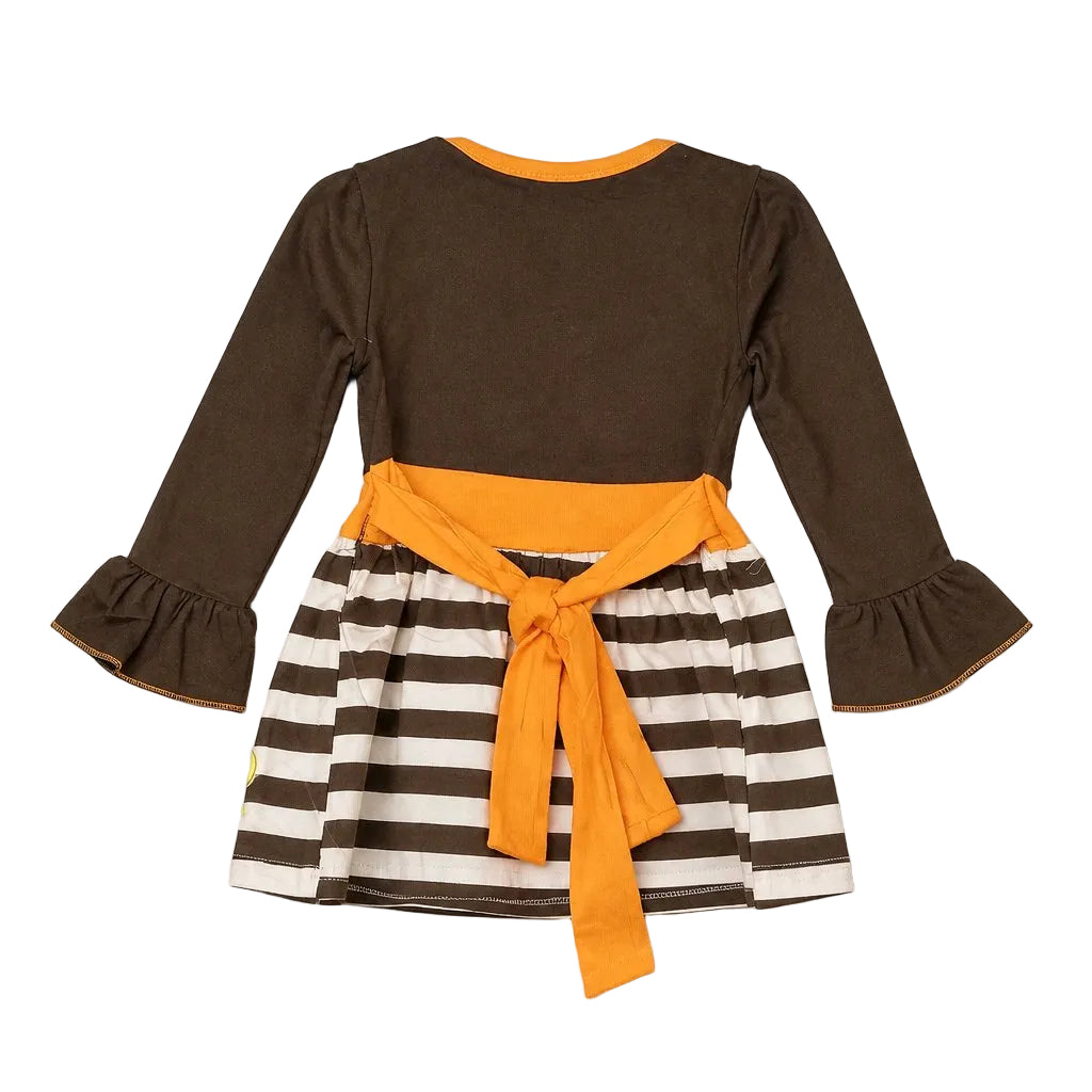 A toddler's long-sleeve dress shown from the back, featuring a solid dark brown upper body, a brown and white striped skirt, and a bright orange waist tie and collar trim, laid flat on a neutral gray background.