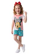 Young girl wearing a Minnie Mouse outfit with a pink shirt and blue shorts on a white background