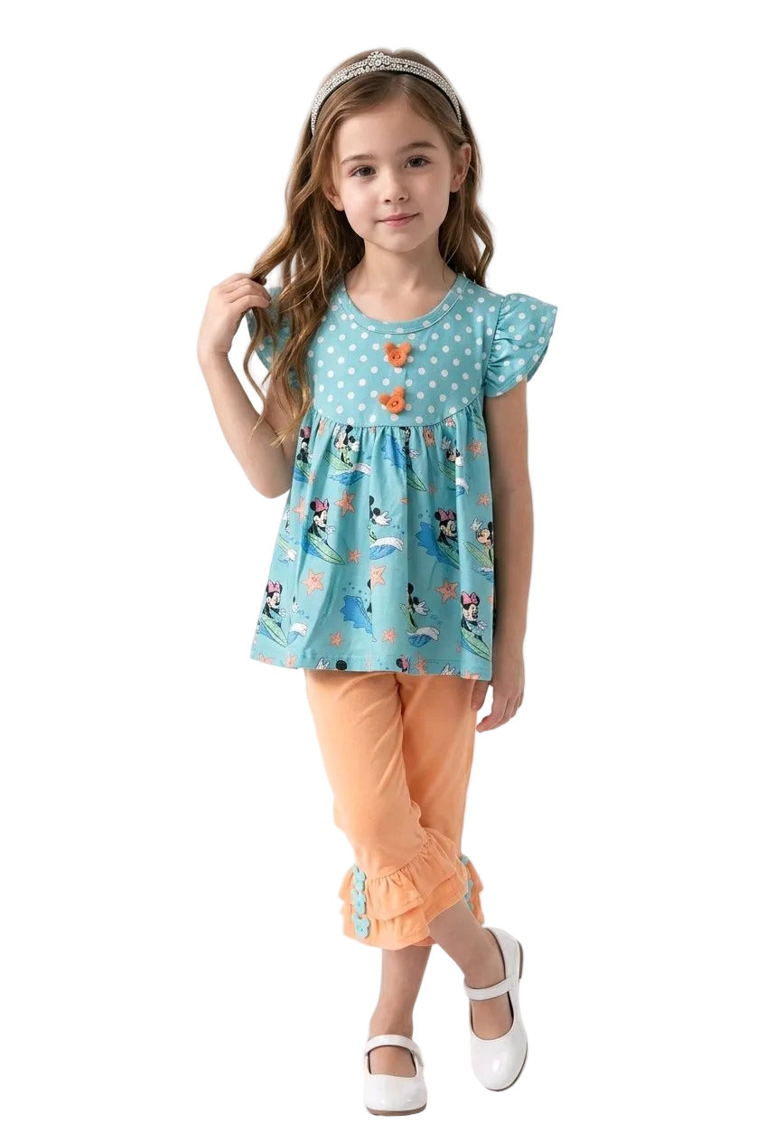 Young girl wearing a blue floral top and orange pants on a white background. minnie mouse set 