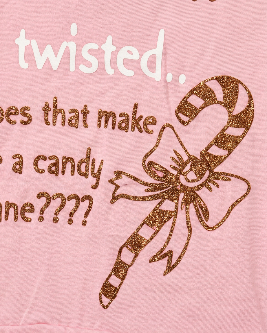 A close-up of a pink garment featuring a brown glitter candy cane graphic tied with a bow and white text that reads 'twisted.