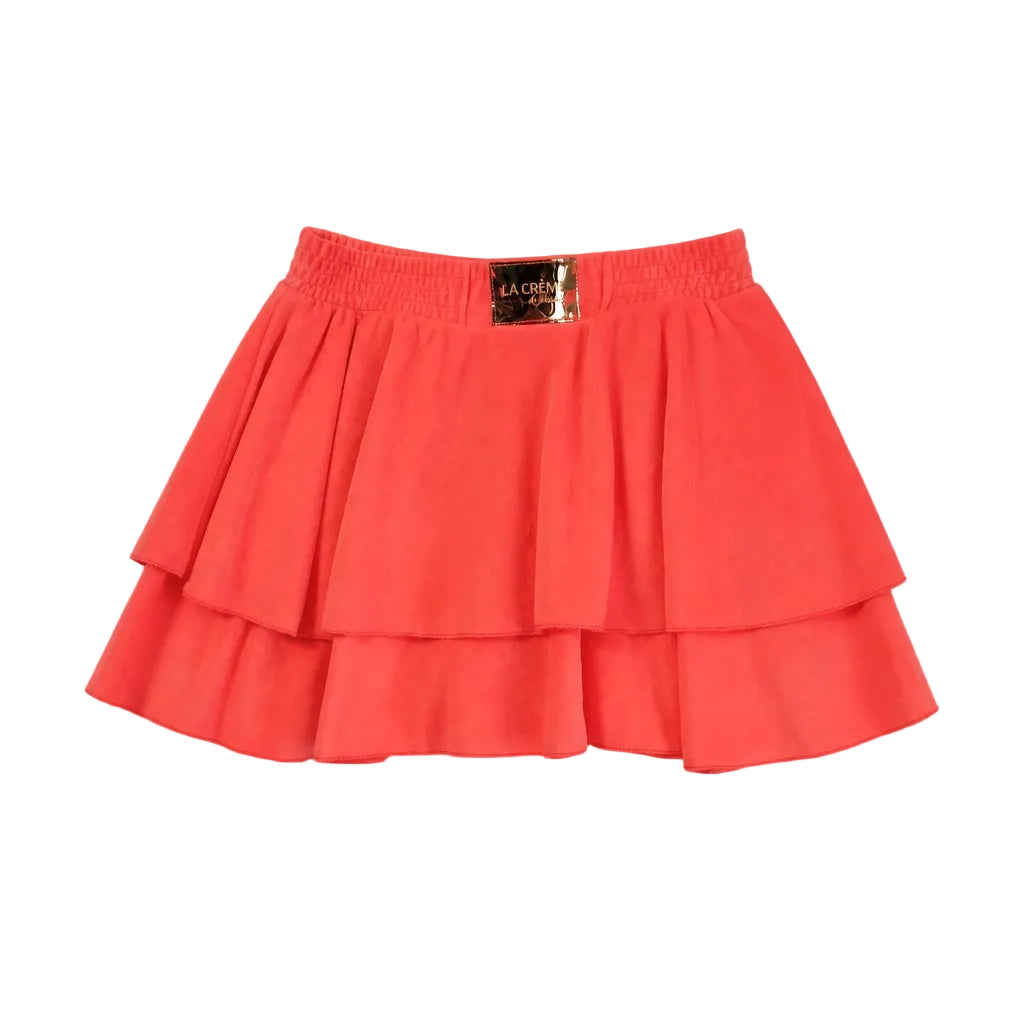 Coral layered skirt with a brand label on a light gray background