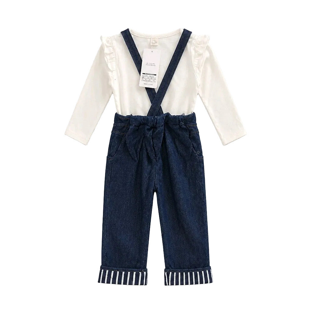 A baby girl's two-piece outfit featuring a white long-sleeve top with ruffled shoulders and dark blue denim suspenders on matching pants with striped cuffs, shown flat on a light gray background.