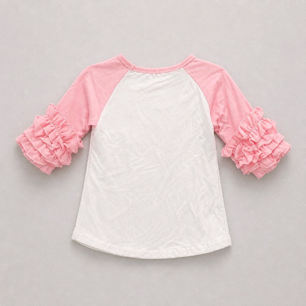 A children's raglan-style top with a white body and pink sleeves, featuring layered ruffle details on the sleeves, laid flat on a light gray background.