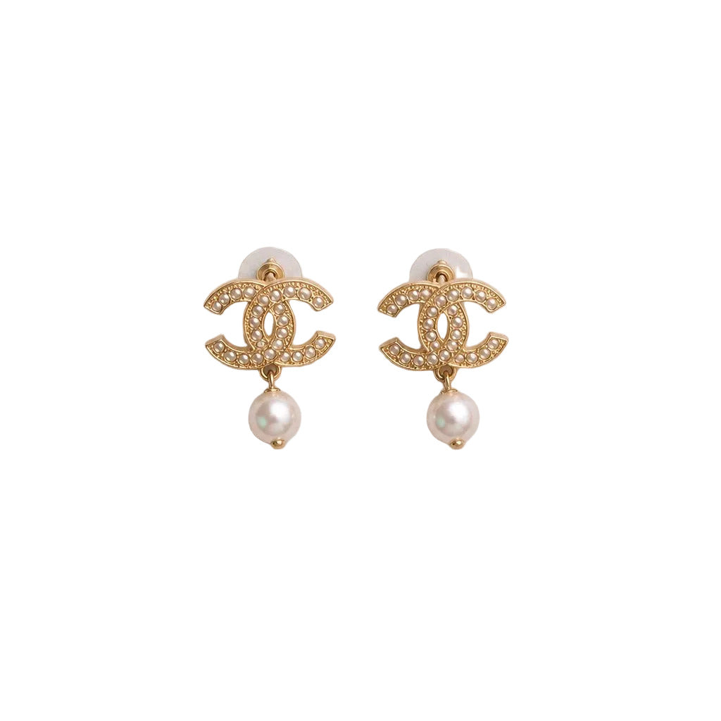 Gold earrings with pearl drops on a light gray background