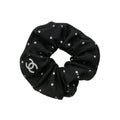 Black scrunchie with white polka dots and a logo on a light gray background