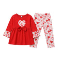 A two-piece toddler girl's outfit set featuring a red long-sleeve top with a heart-patterned bow and cuffs, paired with white leggings covered in a red and pink heart pattern, laid flat on a light gray background.