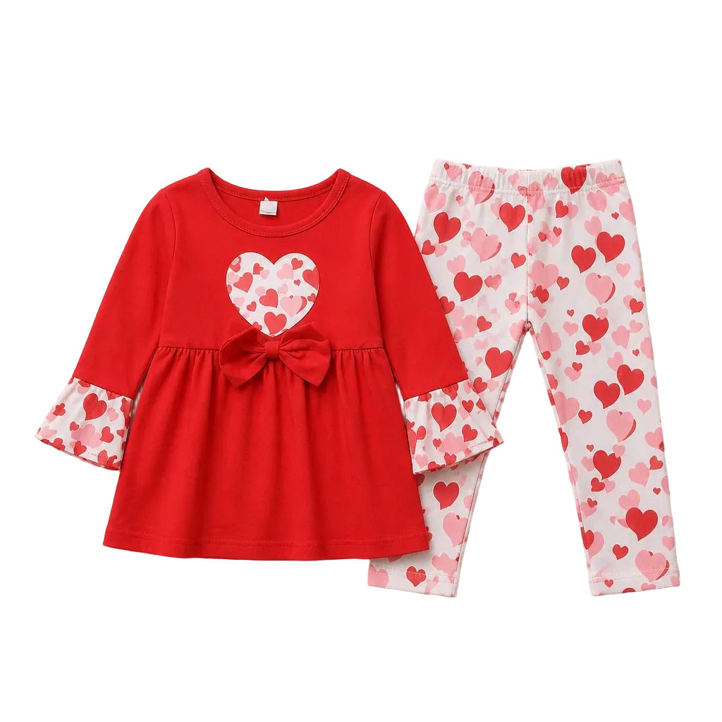A two-piece toddler girl's outfit set featuring a red long-sleeve top with a heart-patterned bow and cuffs, paired with white leggings covered in a red and pink heart pattern, laid flat on a light gray background.