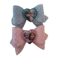 Two glittery hair bows with character designs on a white card. Frozen bows 