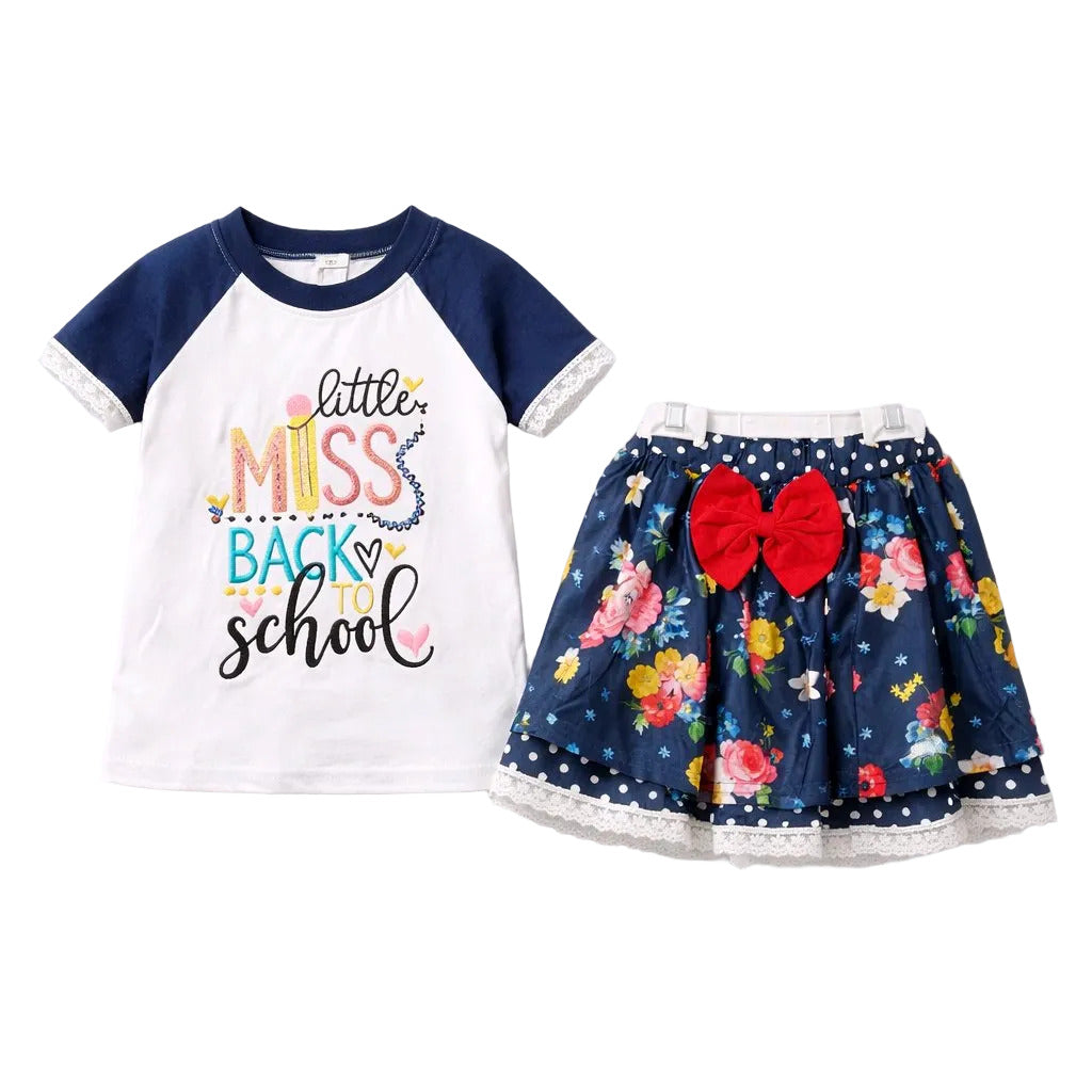 Children's outfit with 'little miss back to school' shirt and floral skirt on a white background