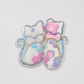 Decorative cat-shaped patch with sequins and pastel colors on a light gray background