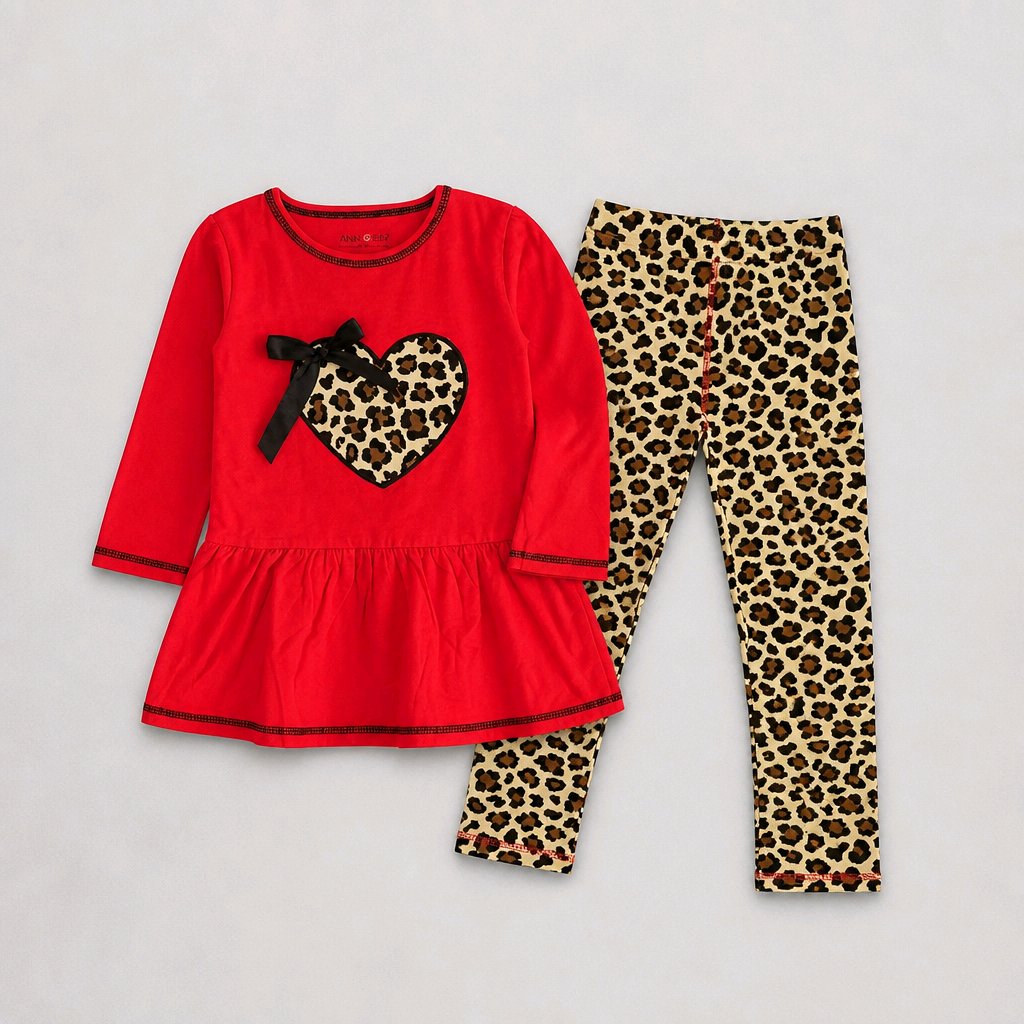 A two-piece children's outfit set featuring a bright red long-sleeve tunic top with a leopard-print heart and bow on the chest, paired with matching leopard-print leggings, laid flat on a light gray background.